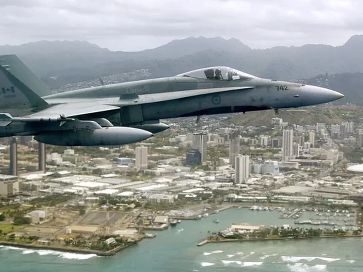 Canadian CF-18 fighter aircraft flying above a coastal city